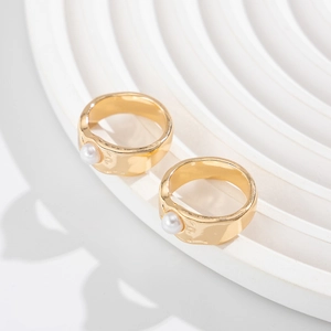 Macro detail of two gold plated liquid lava rings with baroque faux pearl inlays