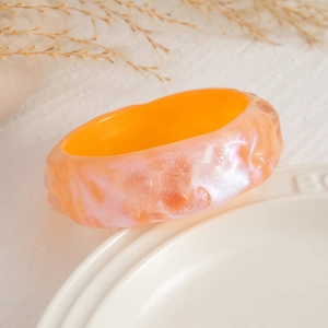 Detalle de brazalete de resina con degradado rosa naranja y textura ondulada irregular