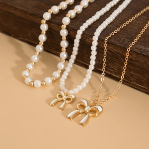 Three-style set of bow pendant necklaces featuring gold chains and faux pearl strands