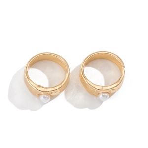 Detailed macro of two gold flower lava rings with baroque pearls on white background