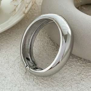 Close-up of polished silver metal bangle showing hinge and spring clasp detail