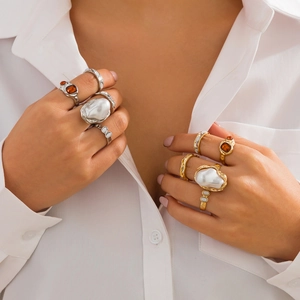 Detail of hand wearing liquid lava flower rings with baroque pearls and orange gemstones