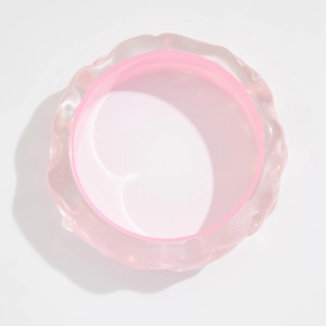 Primer plano de pulsera de resina rosa translúcida con texturas onduladas y banda interior lisa