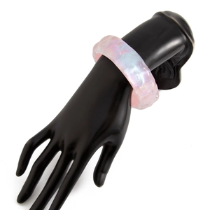 Primer plano de un brazalete ancho de resina rosa irisada con acabado de nácar brillante