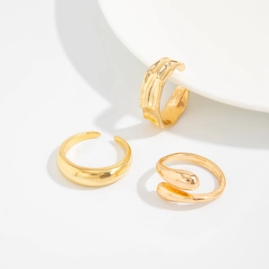 Detailed close-up of a three-piece gold minimalist irregular textured ring set on ceramic