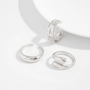Three-piece silver ring set featuring hammered textures and smooth drop-shaped designs