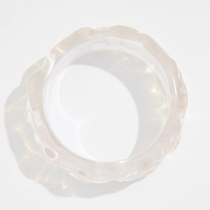Detalle de brazalete de resina transparente con textura ondulada y acabado brillante