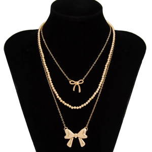 Detailed view of triple-layered gold bow necklace set on black velvet neck model