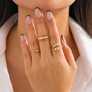 Close-up of three-piece gold metal rings set with polished finish on model's hand