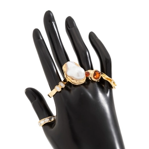Golden liquid lava ring with baroque pearl and orange gemstones on a black hand model