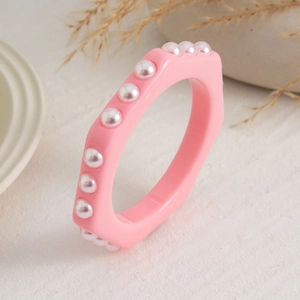 Detalle macro de pulsera hexagonal rosa de resina con perlas blancas incrustadas