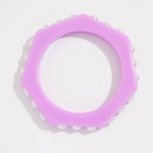 Vista detallada de una pulsera de resina morada con ondas y perlas de imitación blancas