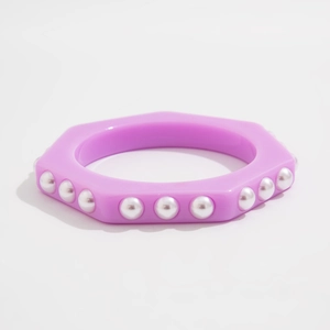 Primer plano de un brazalete hexagonal de resina morada con detalles de perlas de imitación