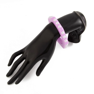 Detalle del brazalete de acrílico morado con perlas en un soporte de mano