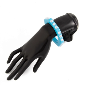 Vista de detalle del brazalete ancho de acrílico azul claro con perlas en un modelo