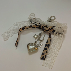 Dettaglio fiocco leopardato con pizzo e ciondoli a cuore e stella in argento