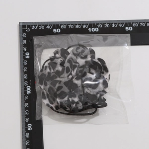 Dettaglio del choker a fiore in tessuto leopardato con elastico su righello di misura