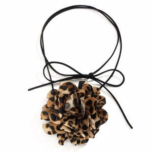 Dettaglio macro del choker con fiore in tessuto leopardato e fiocco di nastro nero