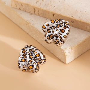 Dettaglio di orecchini d'argento con stampa leopardata su sfondo di pietra naturale