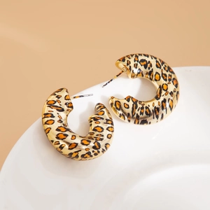 Dettaglio degli orecchini a cerchio a C con stampa leopardata su piatto in ceramica