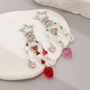 Détail de breloques fraises rouges et roses avec perles et fermoirs étoiles argentés