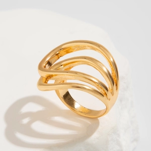 Nahaufnahme des goldenen mehrlagigen Wellenrings auf weißem Steinhintergrund