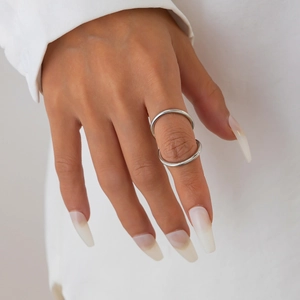 Detailaufnahme eines polierten silbernen Doppelring-Knöchelrings an der Hand eines Models