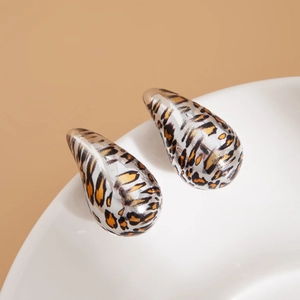 Dettaglio di orecchini a goccia in resina leopardata su un piatto di ceramica bianca