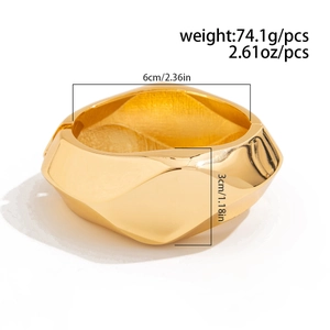Close-up of golden geometric faceted bangle with spring hinge and polished finish