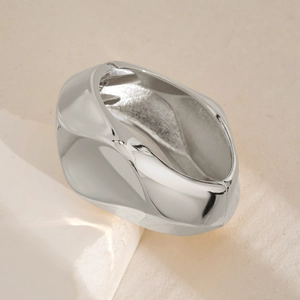Detalle macro del brazalete geométrico de plata pulida con superficie metálica irregular
