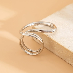 Macro detail of silver liquid metal layered wavy ring on a natural stone surface