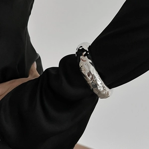 Macro detail of silver wide metal bracelet with unique irregular hammered texture on wrist