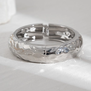 Detail of silver bangle showing hammered texture and polished metal surface with hinge