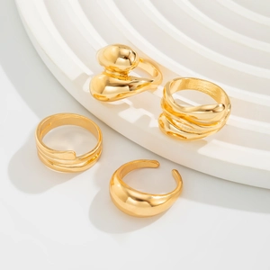 Macro detail of four gold-plated minimalist rings on a white tiered display stand