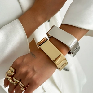 Macro-opname van brede goud- en zilverkleurige armbanden met dikke gelaagde ringen