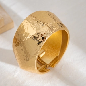 Macro shot of gold liquid metal bangle featuring a hammered texture and spring hinge closure