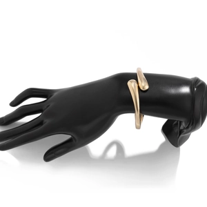 Detail of a minimalist gold teardrop clasp bracelet with a polished mirror finish surface