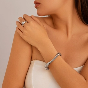 Polierter silberner Armreif und Ring im Liquid-Metal-Design an einem Frauenarm