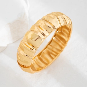 Macro shot of polished gold wide cuff bracelet featuring unique wavy texture design