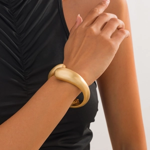 Close-up of matte gold statement bracelet with sleek organic waterdrop design and hinge