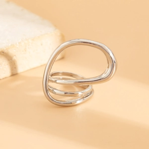 Detail view of silver multi-layer irregular twisted metal ring on a textured stone