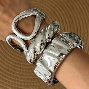 Macro shot of silver chunky metal bangles with twisted and textured geometric patterns