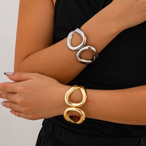 Macro detail of chunky irregular hollow cuff bracelets in polished gold and silver finishes