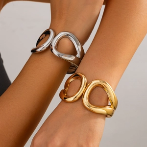Detail view of abstract cutout gold and silver bracelets on a wrist with metallic finish