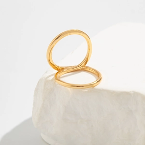 Detail van in elkaar grijpende geometrische gouden ringen op witte gestructureerde steen