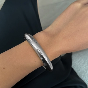 Close-up of polished silver liquid metal chunky bangle showing smooth reflective surface