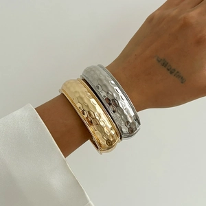 Detailed close-up of hammered gold and silver cuff bracelets with sleek metallic texture