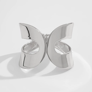 Detail of silver abstract butterfly wing cuff bracelet with polished hollow-out metal
