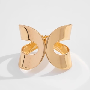 Detailed close-up of a wide hollow geometric gold cuff bracelet with high-polish finish