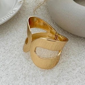 Detailed macro view of gold-finished wide geometric bangle with brushed metal texture